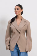 Woman wearing a beige blazer over a blue top on a white background